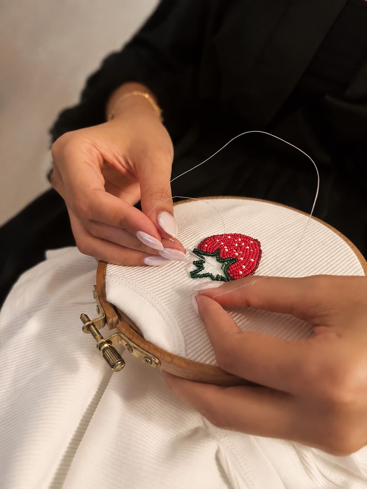 Hands beading a tank top, close up